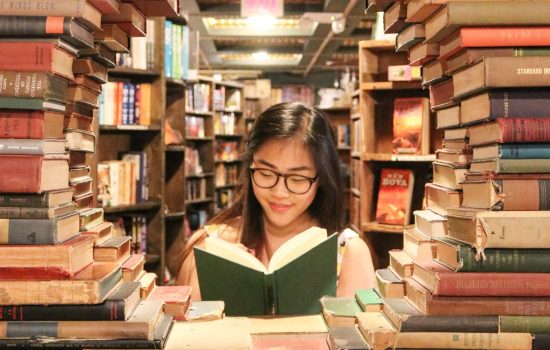 Student in library surrounded by books